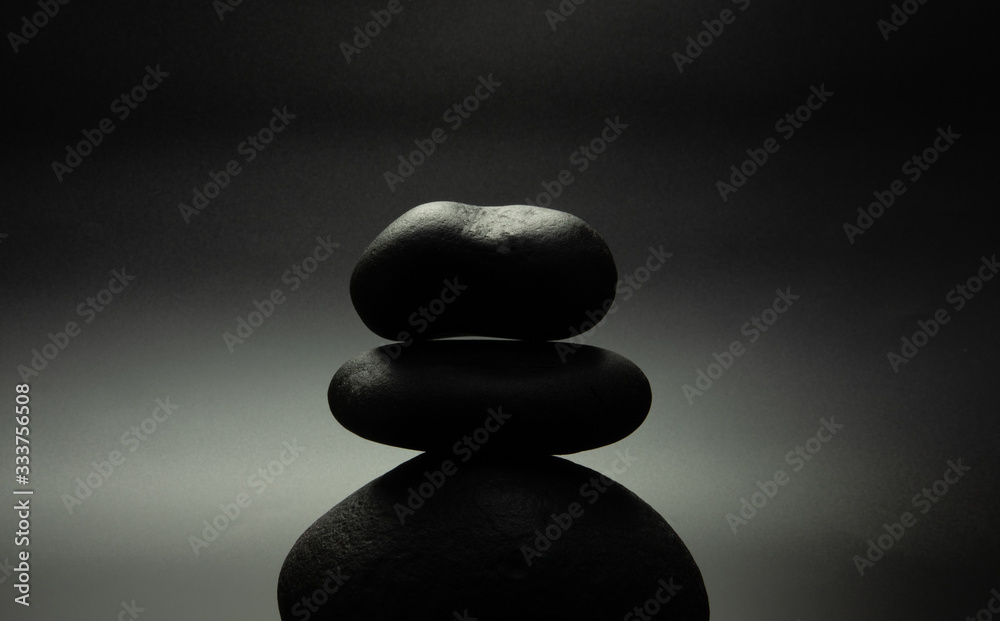 black stones in the shape of a pyramid, black background with backlight black stones in the shape of a pyramid, black background with backlight