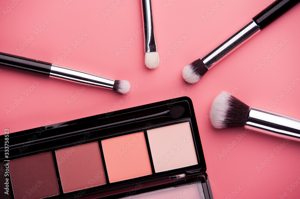 Cosmetic palette with brushes lies on a pink background Cosmetic palette with brushes lies on a pink background