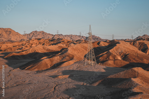 High voltage power lines of Aqaba in the sunset light on the sandstone supply electricity to the city.