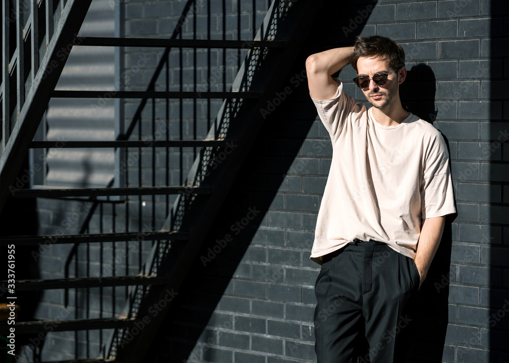 fashion guy posing in sunglasses against a black urban background fashion guy posing in sunglasses against a black urban background