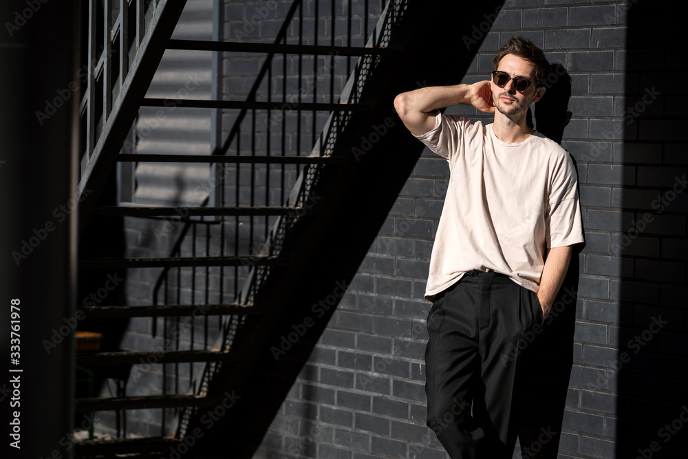 fashion guy posing in sunglasses against a black urban background fashion guy posing in sunglasses against a black urban background