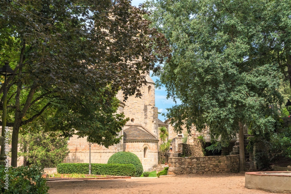 Girona, Spain, August 2018. A fragment of a medieval monastery through the foliage of an old park.