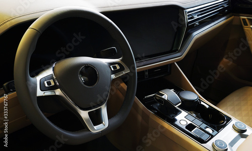 Interior of a modern luxury car, steering wheel with controls, multi-function display, center console with automatic transmission control lever.  © Орлов Александр