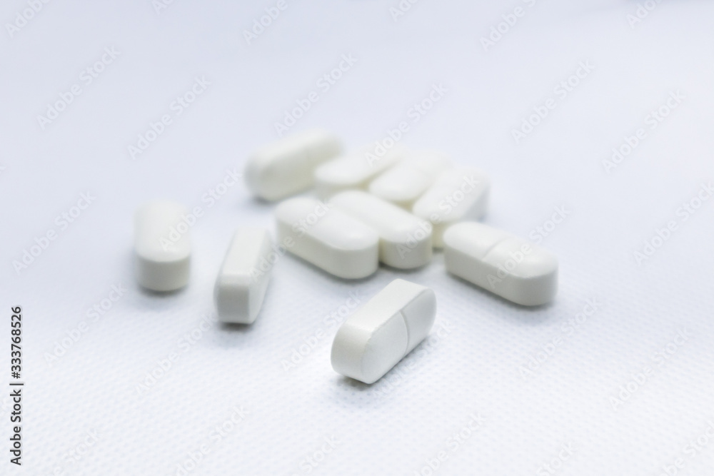 White long health drug pills on white background White long health drug pills on white background