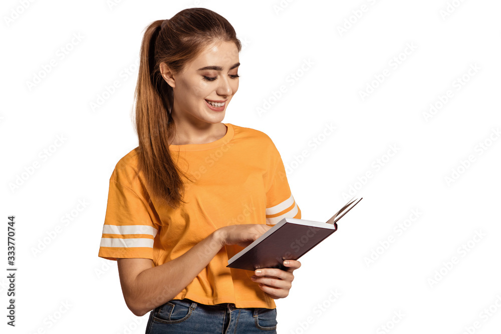 Beautiful, female student in a yellow T-shirt, holds book and is reading. Get an education, prepare for classes in college, institute. Young graduate. White background, isolate. Copy space. Beautiful, female student in a yellow T-shirt, holds book and is reading. Get an education, prepare for classes in college, institute. Young graduate. White background, isolate. Copy space.