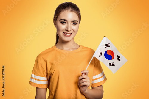 A beautiful young woman holds in her hands the flag of Korea. Exchange student, learn language. Tourist traveling. Football fan. photo