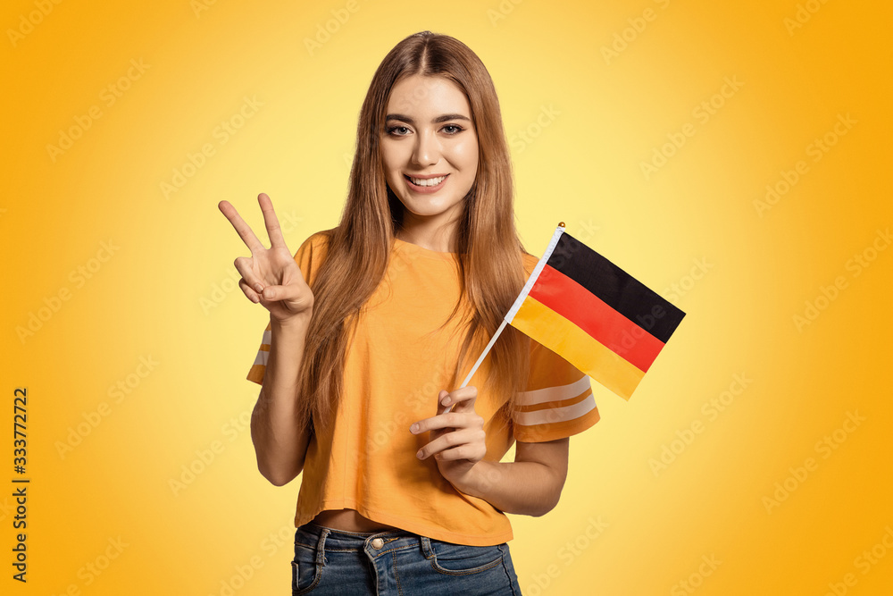 A beautiful young woman holds in her hands the flag of Germany and shows the OK sign. Exchange student, learn Germanic language. Tourist traveling. Football fan. A beautiful young woman holds in her hands the flag of Germany and shows the OK sign. Exchange student, learn Germanic language. Tourist traveling. Football fan.