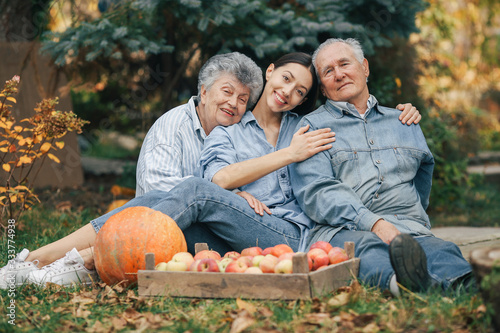 Senior with box of apple. Brunette in a blue shirt. Grandparents with grandaughter.