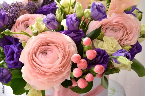 Beautiful pink ranunculus flower with soft focus violet spring flowers and pink decorative berries on background. Elegant bunch of spring flowers. Easter gift. Seasonal spring flowers