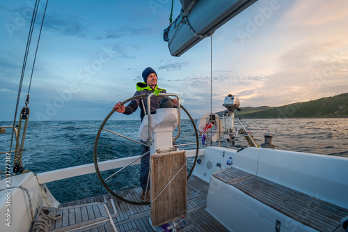 Sailboat helmsman at his watch with beautiful sunset near Campbeltown, Scotland photo