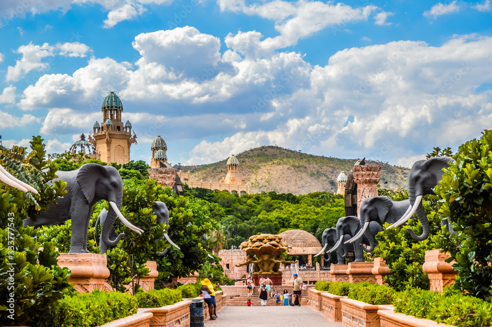 Entrance of The Palace / Lost City /Sun City with stone statues under blue and cloudy sky - obrazy, fototapety, plakaty 