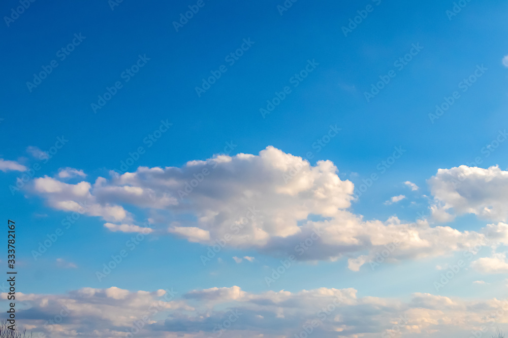 Light blue sky with white curly clouds_