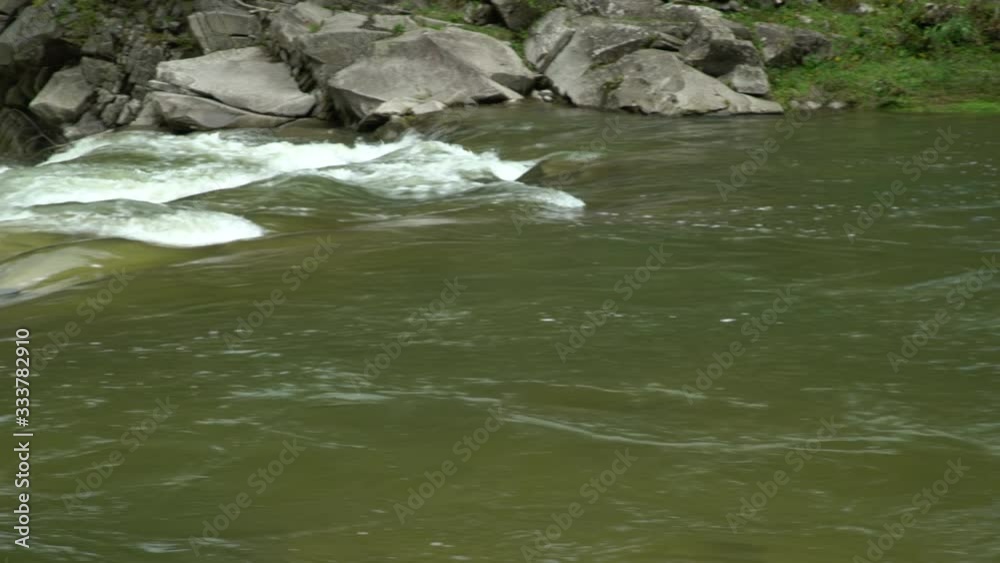 Swift mountain river. Powerful flow. Daylight. Close-up Swift mountain river. Powerful flow. Daylight. Close-up