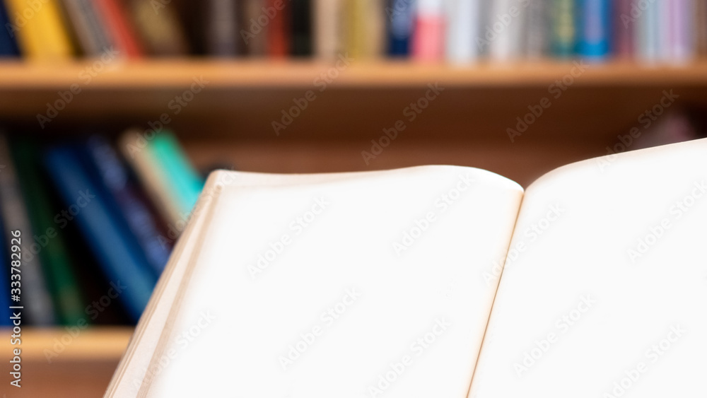 Opened book with blank pages on bookshelf background. Copy space Opened book with blank pages on bookshelf background. Copy space