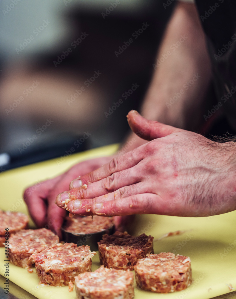 Male Chef hands Making Round Pork Cutlets on yellow cutting board