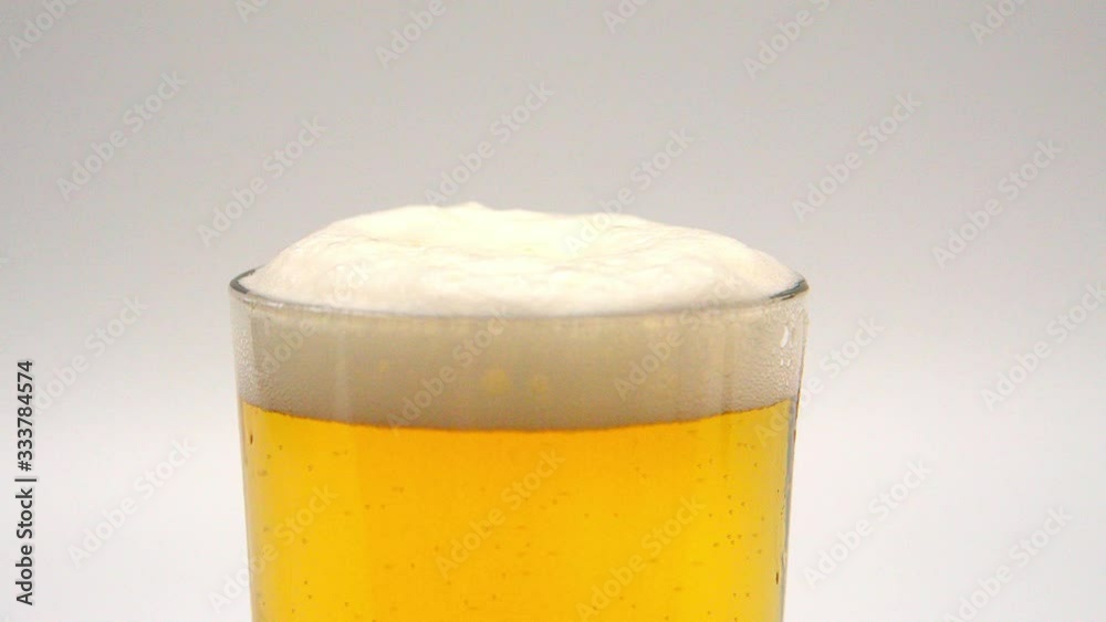 A glass of fresh beer in slow motion - pure refreshment A glass of fresh beer in slow motion - pure refreshment