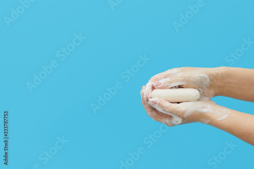 Hand hygiene concept. Female hands are holding antibacterial soap with foam on a blue background. Hand antiseptic during the coronovirus pandemic