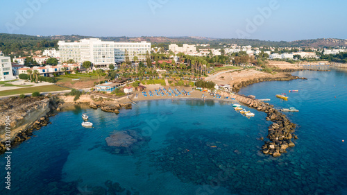 Fototapeta Naklejka Na Ścianę i Meble -  Aerial bird's eye view of Green bay in Protaras, Paralimni, Famagusta, Cyprus. Famous tourist attraction diving location rocky beach with boats, sunbeds, sea restaurants, water sports from above.