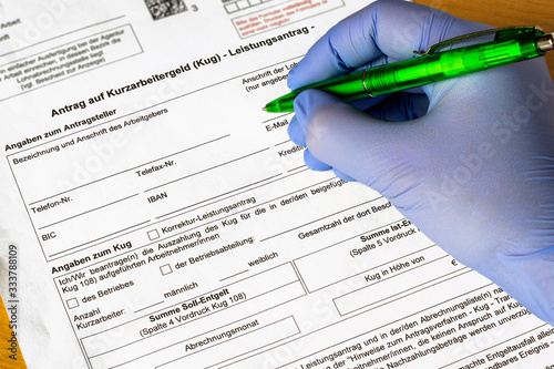 Antrag auf Kurzarbeitergeld wird von einer Person mit medizinischem Schutzhandschuh ausgefüllt