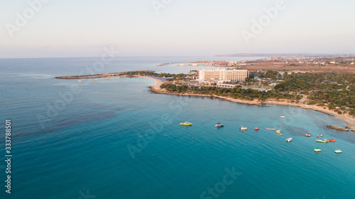 Aerial bird's eye view of Landa beach, Ayia Napa, Famagusta, Cyprus. Landmark tourist attraction golden sand bay at sunrise with boats anchored between Makronissos and nissi in Agia Napa, from above.  © f8grapher
