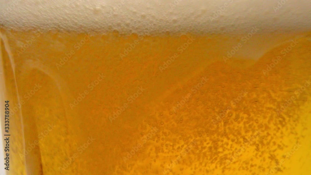 Overflowing glass of fresh beer in slow motion - pure refreshment Overflowing glass of fresh beer in slow motion - pure refreshment