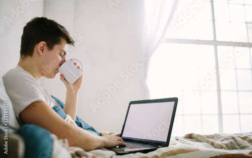 casual young man using laptop in bed at home photo