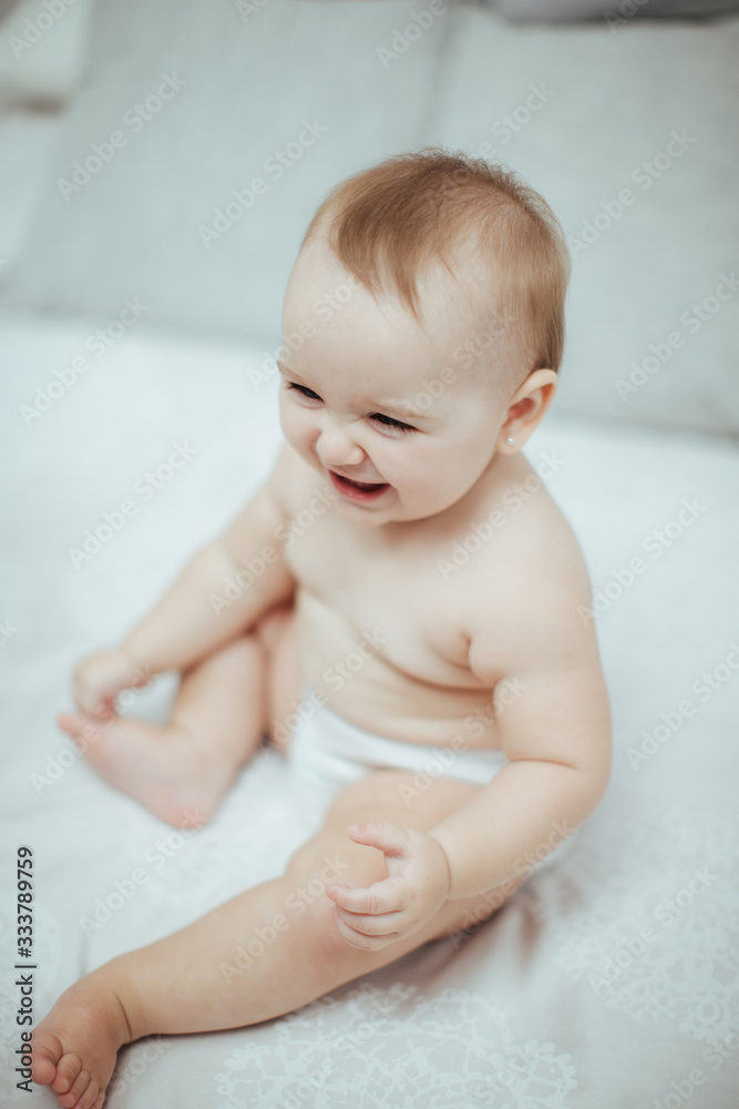 Smiling young little newborn baby girl playing, smiling and posing on the bed Smiling young little newborn baby girl playing, smiling and posing on the bed