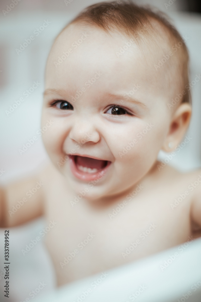 Smiling young little newborn baby girl playing, smiling and posing on the bed Smiling young little newborn baby girl playing, smiling and posing on the bed