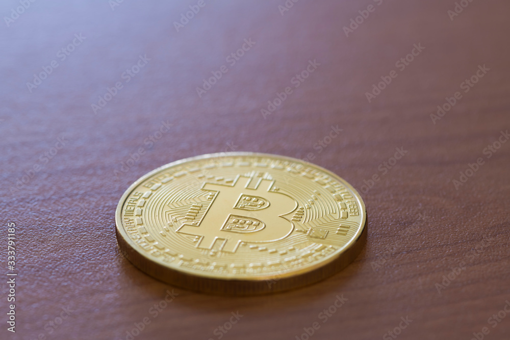 A bitcoin coin on a brown table A bitcoin coin on a brown table