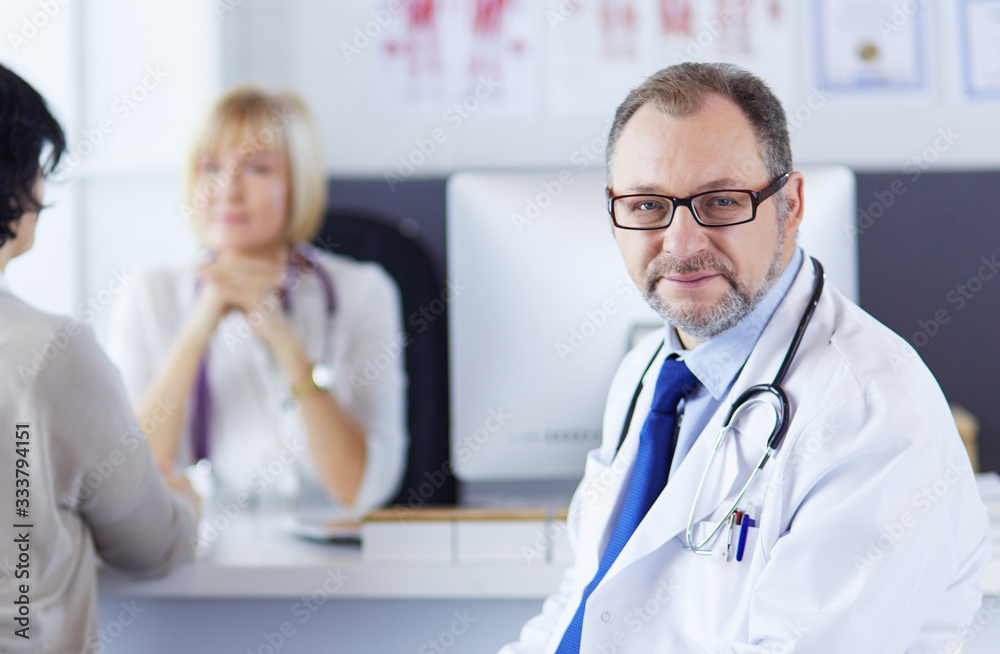 Portrait of senior doctor in office sitting at the desk