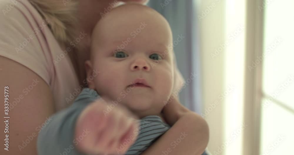 Portrait of funny baby looking into camera and smiling on mother's hands Portrait of funny baby looking into camera and smiling on mother's hands