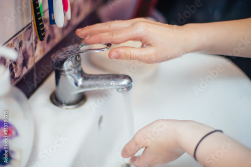 child closes faucet with flowing water. Saving water. cleaning hand to stop spread of Covid-19,Coronavirus pandemic