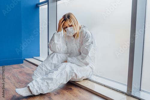 Wallpaper Mural Sad doctor holding hand over head and sitting on the floor near window in hospital because of coronavirus epidemy. Portrait of upset, tired and worried doctor woman thinking of covid-19 pandemic Torontodigital.ca