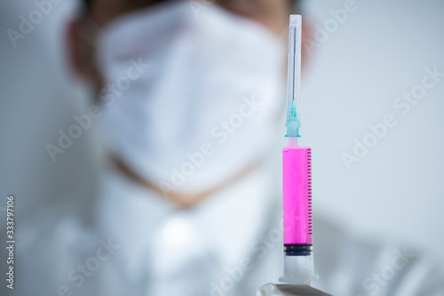 The doctor is holding one vaccines in his hand. Vaccines in purple colors. Studio shooting. Close up.