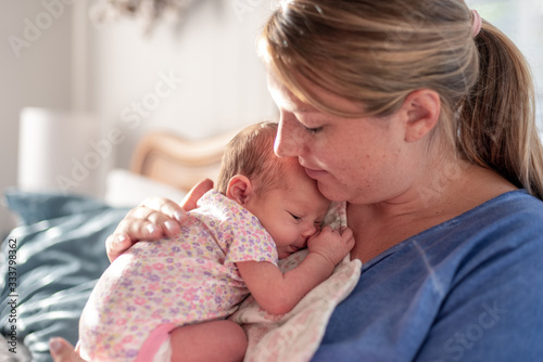 Fotografie Young mom patting baby girl's back for burp after breastfeeding