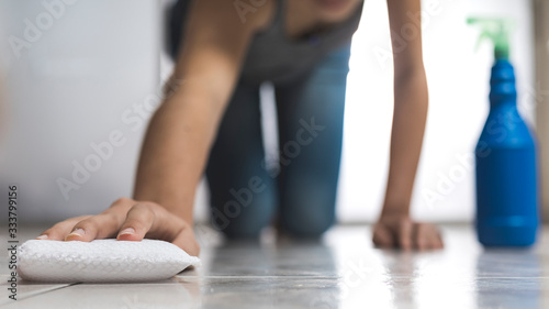 woman disinfecting floor with sponge and spray