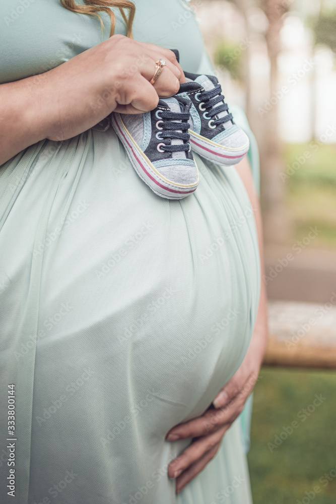 Small shoes newborn baby in belly of pregnant woman. preganancy concept