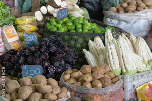 Corn, purple corn, potatoes, lime and cassava displayed with prices at a local grocery