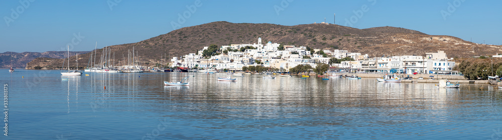 Panorama of Adamas village with boats and mountain reflecting in Milos bay