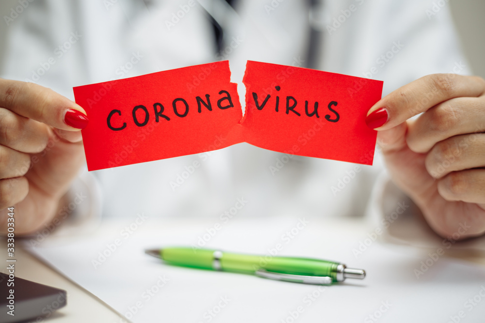 Doctor woman with surgical mask tearing a red paper with mesaage Coronavirus, isolated on gray background. Female nurse holding nCov2019 sign. Covid-19 and sickness prevention concept. Doctor woman with surgical mask tearing a red paper with mesaage Coronavirus, isolated on gray background. Female nurse holding nCov2019 sign. Covid-19 and sickness prevention concept.