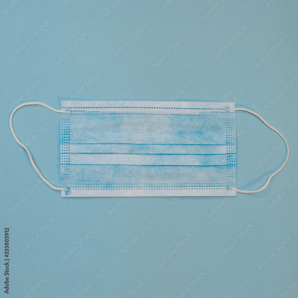 Surgical Ear-Loop mask. Protective medical mask on blue background. Framed in square. Coronovirus, quarantine, epidemic, pandemic, cold,illness. Medicine concept and health