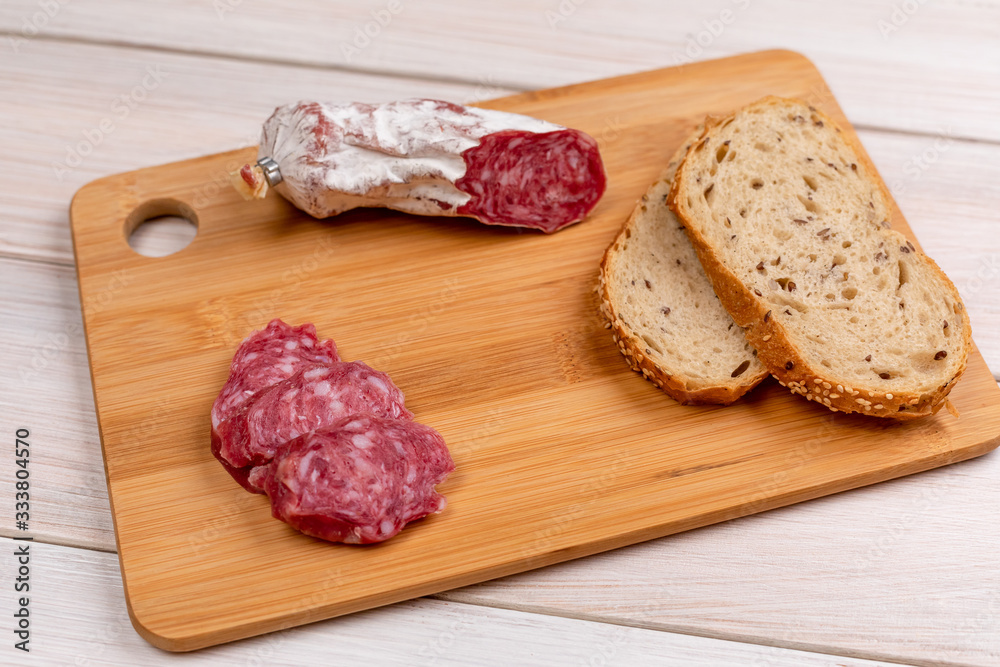 Baked sausage and several sliced sausage slices next to sliced whole grain bread on a wooden board. The concept of simple affordable food. Baked sausage and several sliced sausage slices next to sliced whole grain bread on a wooden board. The concept of simple affordable food.