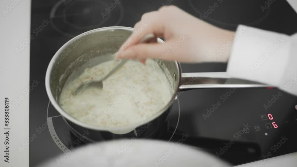 Preparation and Stirring Oatmeal in pan on the kitchen stove Preparation and Stirring Oatmeal in pan on the kitchen stove