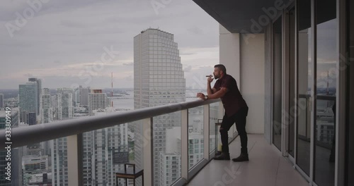 Man smoking cigar on balcony at sunset photo