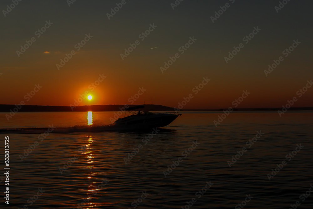 The boat floats on the sea at sunset