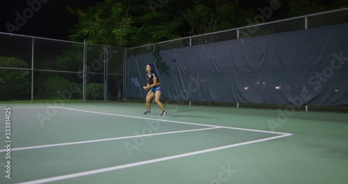 Woman playing tennis at night