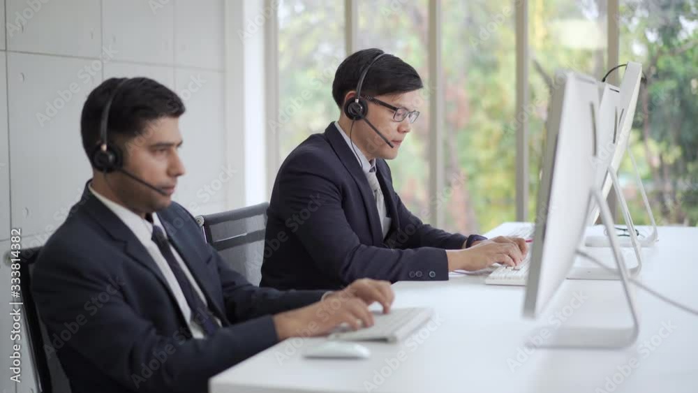 Professional Asian man customer support call center with colleague speaking to client for consulting and solving problem. Telemarketing sales working with computer and talking on phone to customers. Professional Asian man customer support call center with colleague speaking to client for consulting and solving problem. Telemarketing sales working with computer and talking on phone to customers.