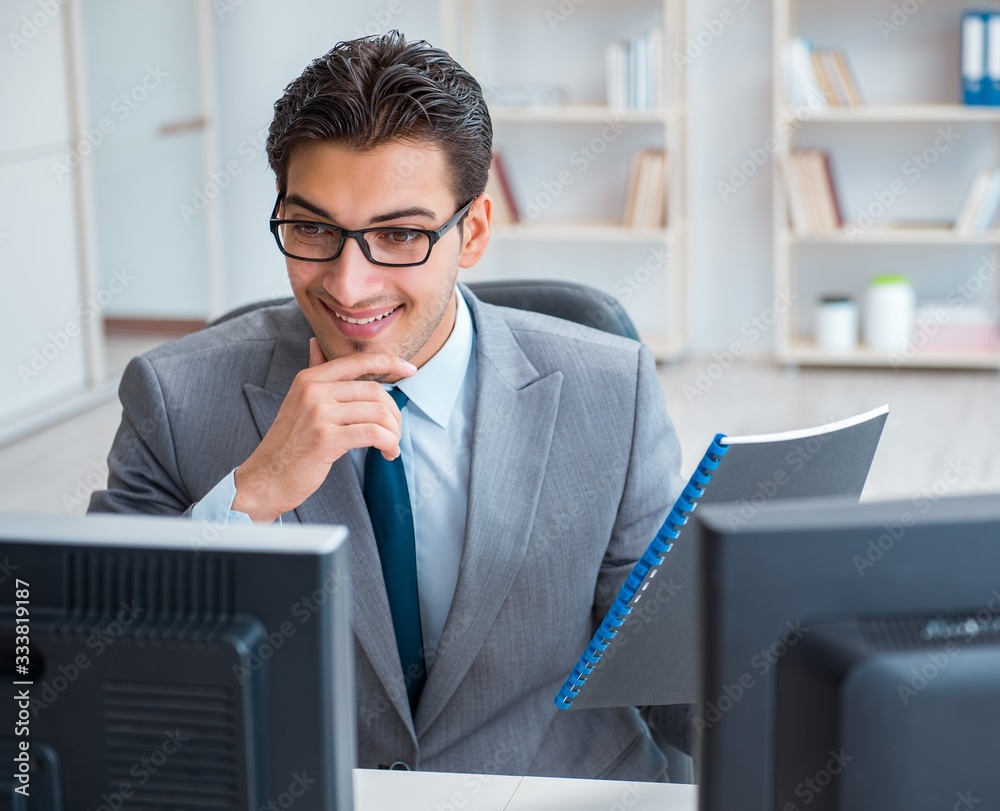Naklejka premium Businessman sitting in front of many screens