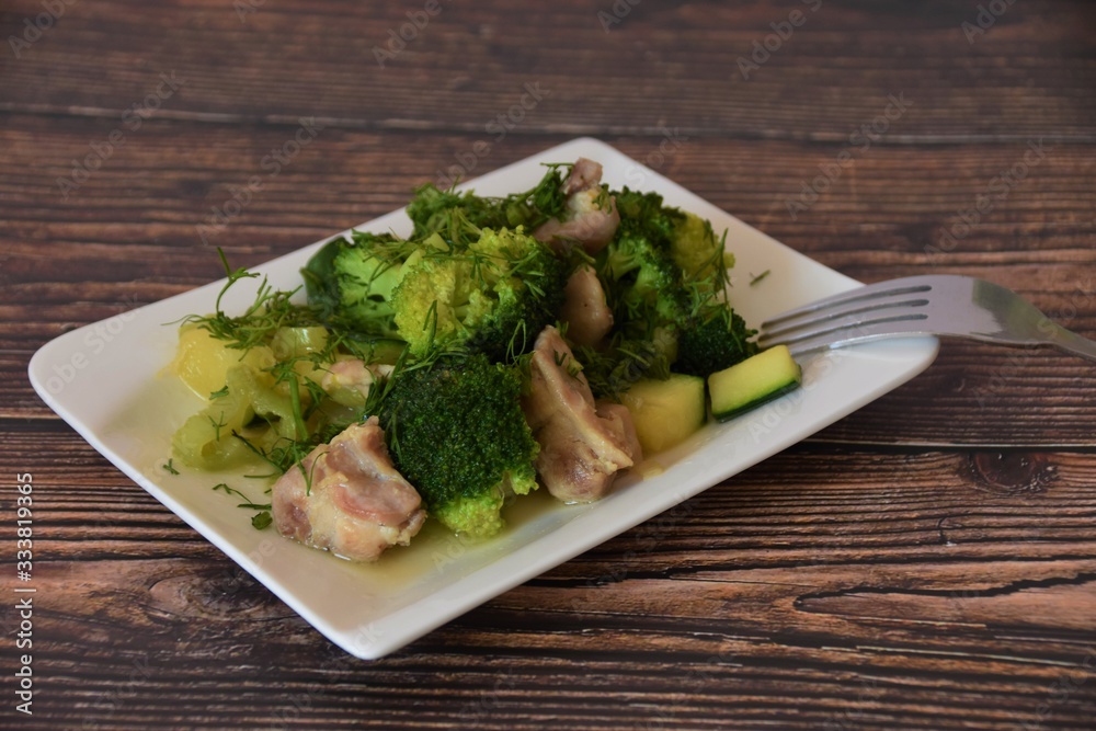 stewed vegetables and pieces of chicken on a white plate on a wooden table stewed vegetables and pieces of chicken on a white plate on a wooden table