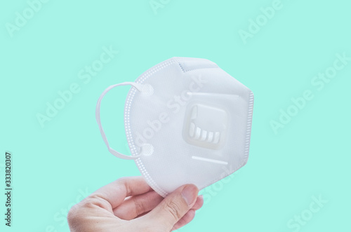 hand holding n95 or kn95 mask for protect corona virus(covid-19).n95 mask with sign of protect covit-19 on green mint background.